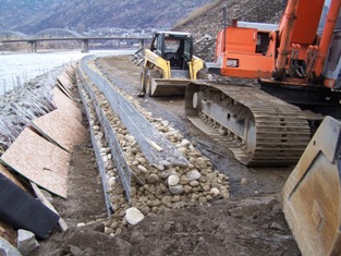 MSE wall constructed above vegetated riprap, cobbles were later placed over wooden sheets